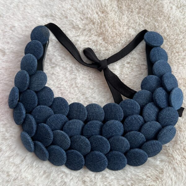 Collier plastron en boutons jean bleu sur fond beige