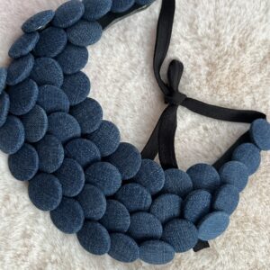 Collier plastron en boutons jean bleu sur fond beige