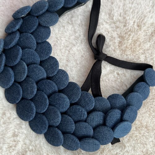 Collier plastron en boutons jean bleu sur fond beige
